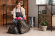 © Pixel-Shot - Young woman putting trash into garbage bags at home