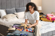 © Pixel-Shot - Beautiful young happy woman with starfish unpacking summer clothes from suitcases at home