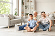 © Pixel-Shot - Teenage boy with his dad and grandfather sitting on floor at home
