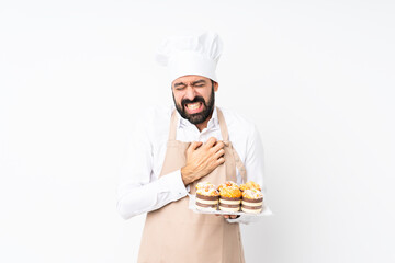 Wall Mural - Young man holding muffin cake over isolated white background having a pain in the heart