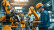 © atitaph - Automation engineers use tablets to program robot arms in a smart factory for digital factory production technology showing industrial automation processes.