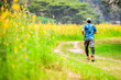 © STOCK PHOTO 4 U - Man Running on a Trail in a Lush Green Field with Yellow Flowers and Trees in the Background