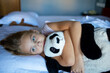 © evgeniia_1010 - A little blonde girl with a teddy bear on a spacious bed in a modern and comfortable beautiful hotel room.