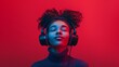 © AounMuhammad - A girl with curly hair enjoying peaceful music with eyes closed from big black headphones ,solid red studio color background , blue high neck . Headphones and music ad concept