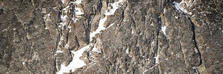 Wall Mural - Rock texture. Snow and cracks on the surface of the cliff. Natural stone background.