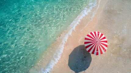 Wall Mural - Aerial view of a red and white striped umbrella on a pristine sandy beach with crystal clear turquoise waters gently lapping the shore.