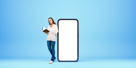 Wall Mural - Woman with a book and mock up smartphone display on blue background