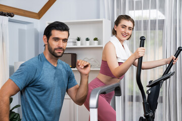 Wall Mural - Athletic and sporty young couple or fitness buddy running on running machine together, home body workout exercise session as healthy sport lifestyle at home. Gaiety home exercise workout training.