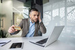 © Liubomir - Man looking worried while shopping online with a credit card in a modern office, expressing concern about an online transaction