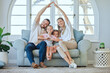 © Delcio Fernandes/peopleimages.com - Portrait, home and happy family with roof hands on sofa for support, security and safety, trust or house insurance. Property, protection or kids with heart emoji for parents, investment and comfort
