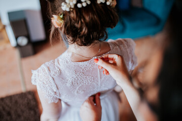 Wall Mural - A bride or bridesmaid carefully adjusts the laces or buttons of a wedding dress, highlighting the detailed preparations and anticipation before the ceremony.