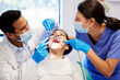 © peopleimages.com - Dentist, team and patient in clinic with equipment for consultation, oral hygiene or medical procedure. Service, doctor man and nurse woman with client for teeth extraction, cleaning or dental care