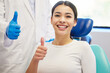 © peopleimages.com - Dentist, client and smile with portrait for thumbs up for success of teeth whitening, oral and dental care. Doctor, assistant and woman with hand gesture for well done or good job, yes and thank you.