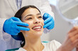 © Lumeez23/peopleimages.com - Woman, dentist and smile with mirror for dental surgery in clinic for teeth whitening and treatment with doctor. Female patient, satisfied and happy on consultation for canal procedure and oral care
