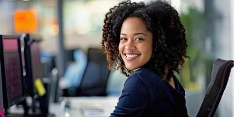 A black woman turning around in an office chair to smile at the camera