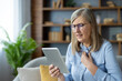 © Liubomir - Elderly woman having a virtual medical consultation on a tablet, expressing concern and pain. Online health examination and patient care.