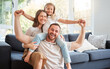 © ChasingMagic/peopleimages.com - Smile, family and portrait on shoulder by sofa for weekend fun, happiness and bonding together. Playful, mom and dad with daughter in living room for support, care and love at home on fathers day