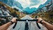 © Cherkasova Alie - A cyclist is riding through a mountainous area, the steering wheel and human hands are visible. The concept of travel and outdoor activities.
