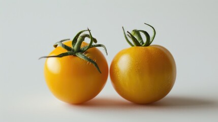 Wall Mural - Two yellow ripe tomatoes standing alone against a white backdrop