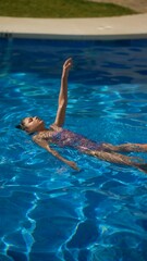 Wall Mural - A young woman enjoys swimming in an outdoor pool