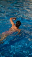 Wall Mural - A young woman enjoys swimming in an outdoor pool