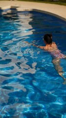 Wall Mural - A young woman enjoys swimming in an outdoor pool