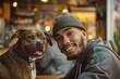 © mattegg - A young, mixed race man smiles for the camera while holding his brown and white dog at a coffee shop