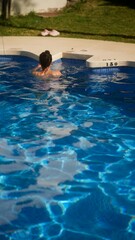 Wall Mural - A young woman enjoys swimming in an outdoor pool