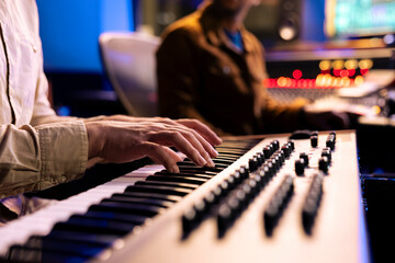 Fototapete - Male singer playing notes on electronic keyboard piano in music recording studio, producing a new hit with midi controller synthesizer. Skilled artist making a live performance in control room.