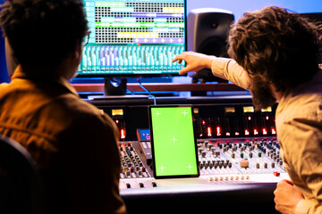 Aufkleber - Singer and producer collaborating on new music for an album, looks at greenscreen on tablet next to control panel board in studio. Expert and musician recording new tracks, mixing console.