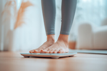 Closeup of feet, Young Asian woman standing on scales to measure her weight at home, Checking result of her slimming diet. Healthy living concept