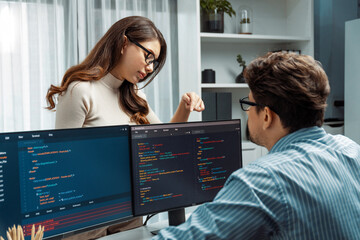 Poster - woman colleague standing opposite to man programmer working on desk to discuss coding website softwa