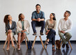 © peopleimages.com - Happy, business people and waiting room with chair for hiring, career or job opportunity at office. Group of employees with candidate standing out on furniture in recruiting for selection or pick