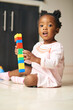 © Seisa/peopleimages.com - Black child, portrait and little girl with blocks, toys or building for creativity or childhood development on floor at home. Young African, baby or toddler playing with colorful shapes for learning