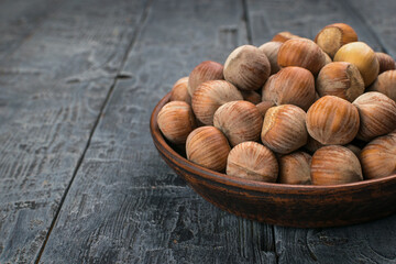 Wall Mural - Rustic Wooden Bowl Filled with Raw Hazelnuts Resting on Weathered Wooden Table