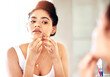 © C Pendl�/peopleimages.com - Skincare, squeeze and face of woman in bathroom for acne, facial and self care with morning routine. Hygiene, inspection and cleaning with girl and popping pimple on cheek for blemish, flaws and scar