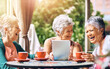 © Cecilie S W/peopleimages.com - Cafe, laughing and tablet with elderly women at table outdoor together for bonding or social media. Funny, happy or smile with senior friends at sidewalk coffee shop, tech for app or memories