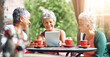 © peopleimages.com - Coffee shop, smile and tablet with senior women at table outdoor together for bonding or social media. Happy, love or smile and elderly friends at sidewalk cafe with technology for app or memories