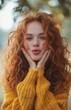 © yevgeniya131988 - Happy young woman with curly red hair blowing a kiss to the camera, wearing a yellow sweater outdoors