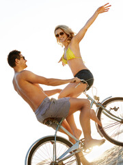 Poster - Happy couple together at beach on bike in sunshine with arms, freedom or date with romance. Man, woman or vintage bicycle by ocean for bonding on fun vacation, balance in summer with people travel