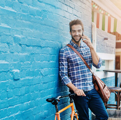 Poster - Portrait, phone call and happy man on bicycle in city for eco friendly transportation by brick wall. Mobile, conversation and person with bike for communication, travel and commute by space outdoor