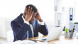 © Prostock-studio - Stressed and overworked african-american young businessman sitting in office with hand on forehead, copy space