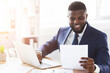 © Prostock-studio - Satisfied african american businessman checking documents in modern office, side view, empty space