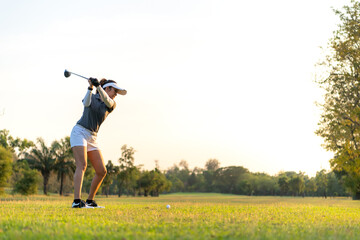 Wall Mural - Golfer women sport course golf ball fairway. People lifestyle woman playing game golf swing tee of on the green grass sunset background. Asian female player game shot in summer. copy space for text