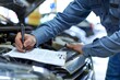 © Cetin - The mechanic is taking notes on the form while he looks at an open car hood
