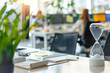 © Victor Bertrand - An hourglass sits on an office desk, symbolizing the passage of time amidst a busy and modern working environment.