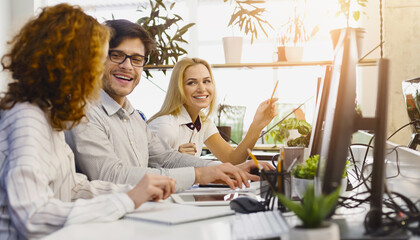 Aufkleber - Diverse Professionals Working Together in Office: A group of diverse young professionals actively collaborating at a bright, contemporary office, buzzing with teamwork and creativity.