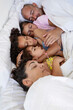 © ADDICTIVE STOCK - Multiethnic family sleeping peacefully in bed together