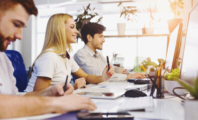 Poster - A team of individuals is seated at a desk, engaged in work on a computer screen. They appear focused and attentive, possibly collaborating on a project or conducting a virtual meeting.