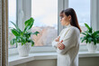 © Valerii Honcharuk - Serious thoughtful middle aged female looking out the window at home